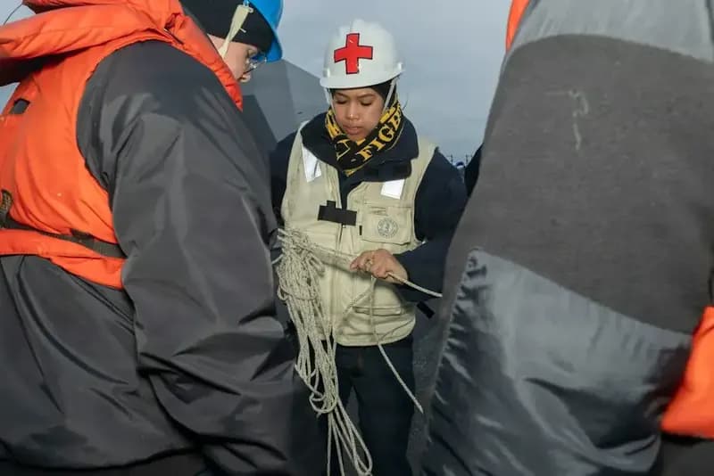 Trainees in life jackets and hard hats handling rope